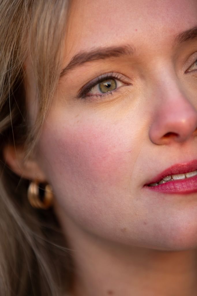 Intimate close-up portrait capturing a young woman wearing earrings.